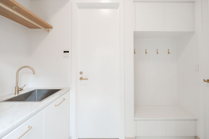Laundry and mudroom with a sink, timber shelf and coat hooks